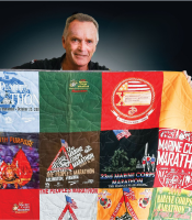older man holding up quilt made of marathon tee shirts