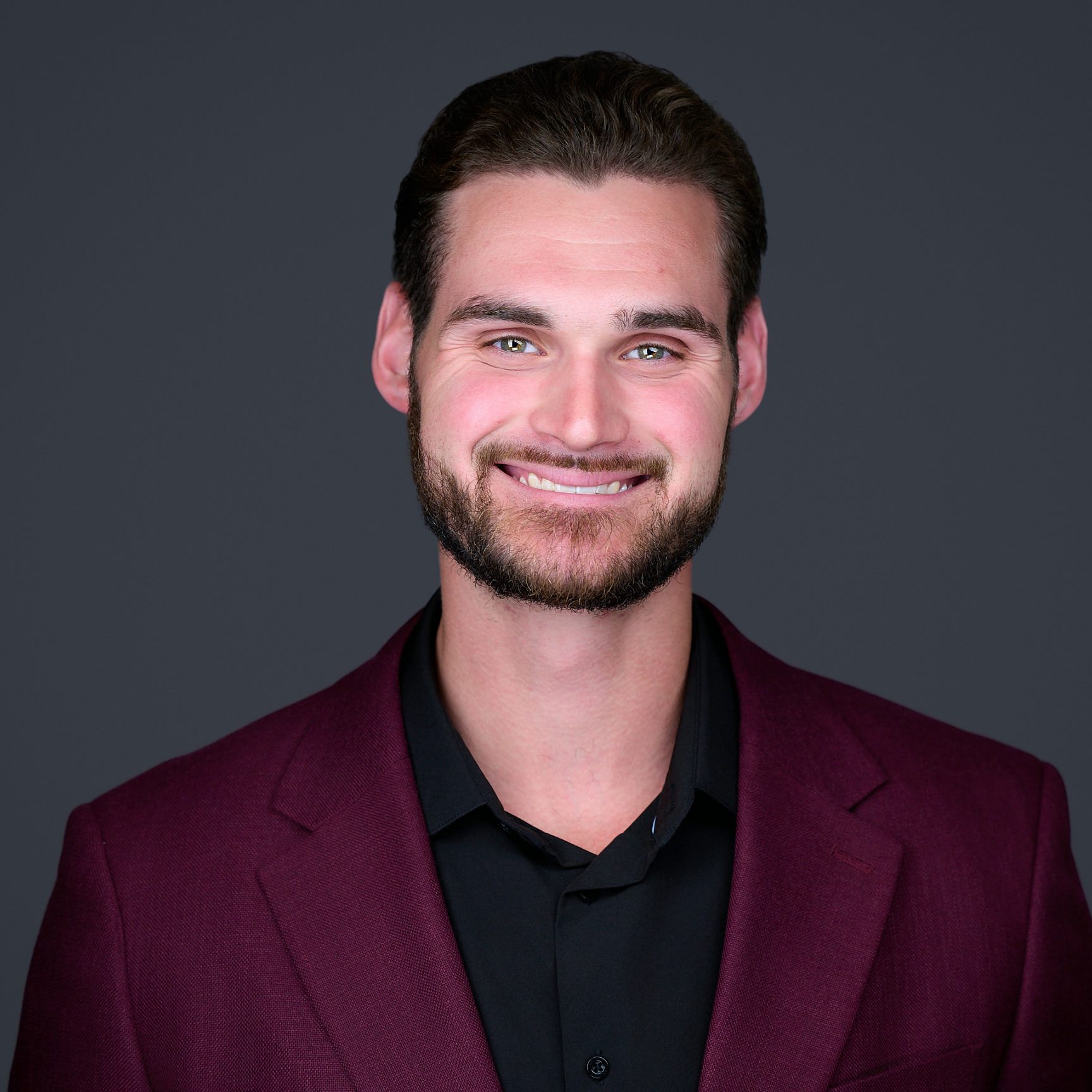 man with brown hair wearing black polo shirt